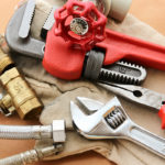 An adjustable wrench, a pipe wrench, a pair of pliers, and a pipe